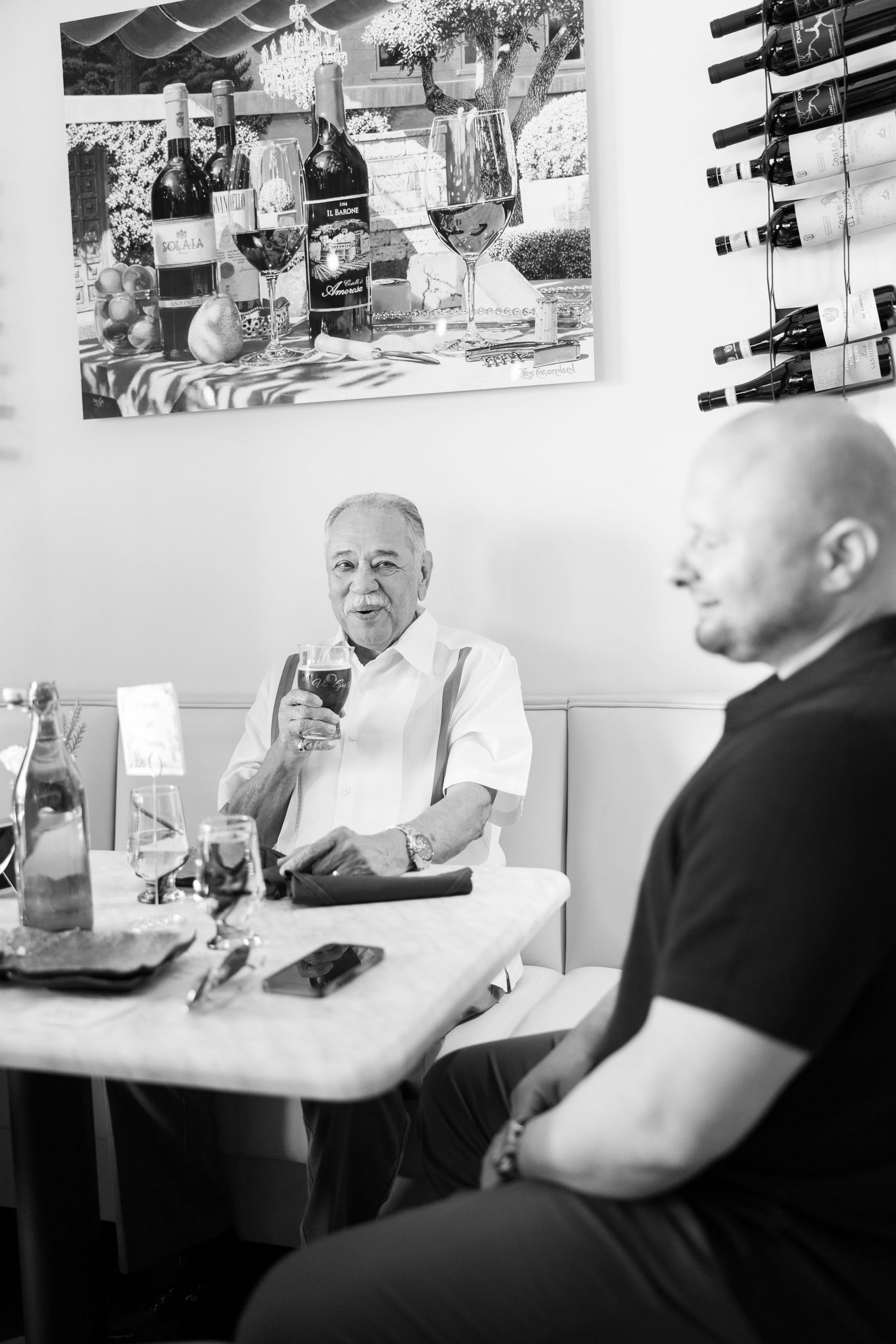 Black and white sequence of casual conversation at diner table with wall art displays.