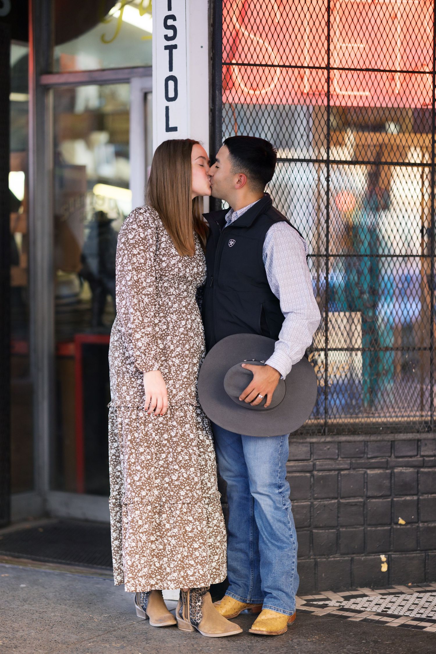 A couple standing together near a metal gate outside a building.