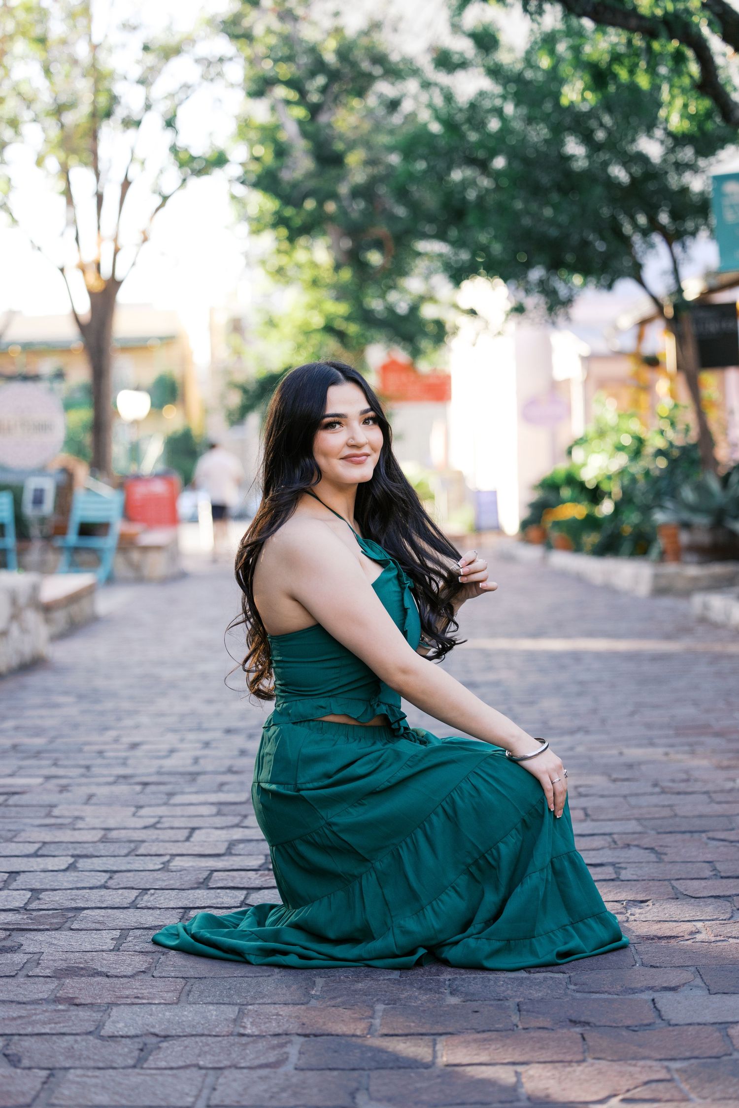 Elegant emerald green dress photoshoot on cobblestone street.
