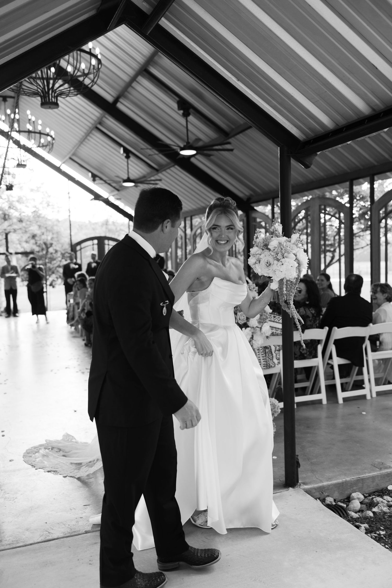 Bride and groom share first look moment under rustic covered outdoor wedding venue.
