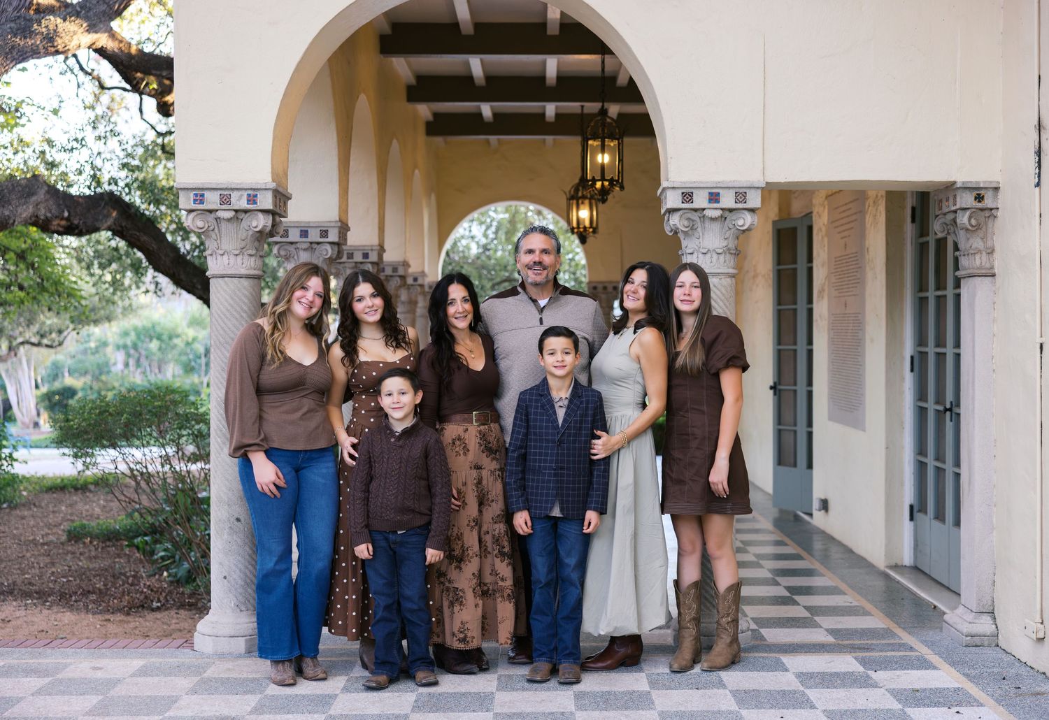 A group poses together under an arched colonnade of a Mediterranean-style building.