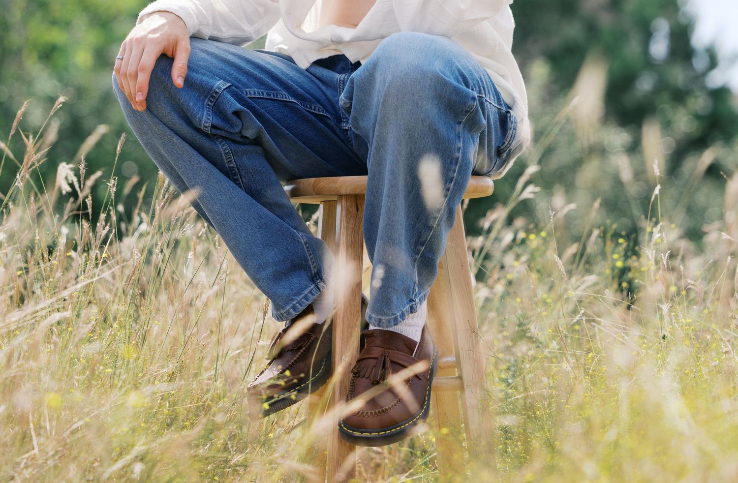 Detail shot of jeans and shoes among tall grass in natural setting.