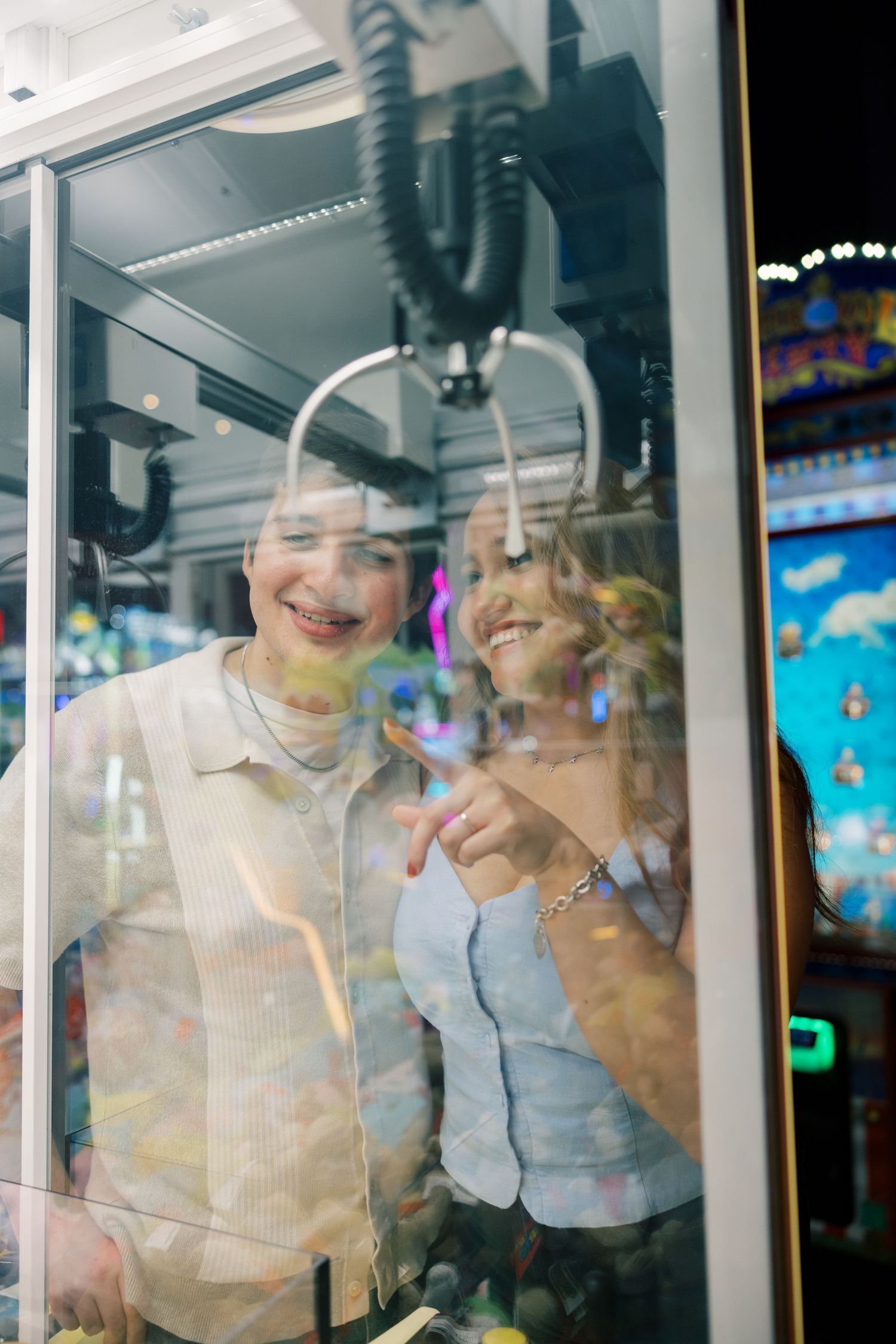 Reflective glass window showing arcade game machines and neon lights.