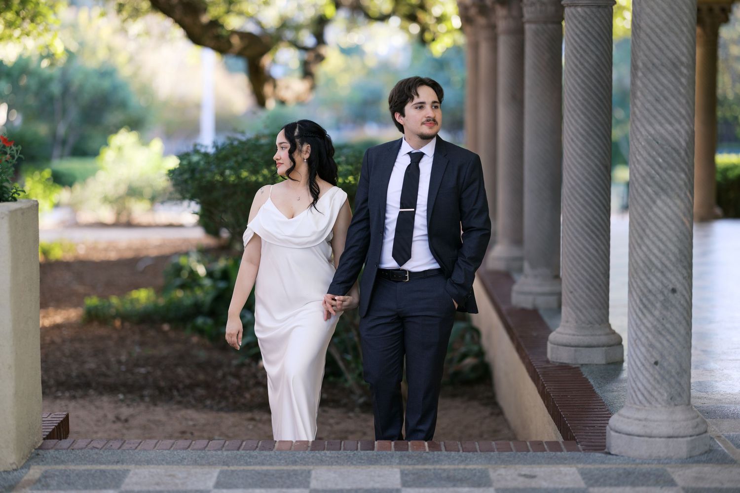 Elegant wedding photos captured along a columned walkway with natural lighting.