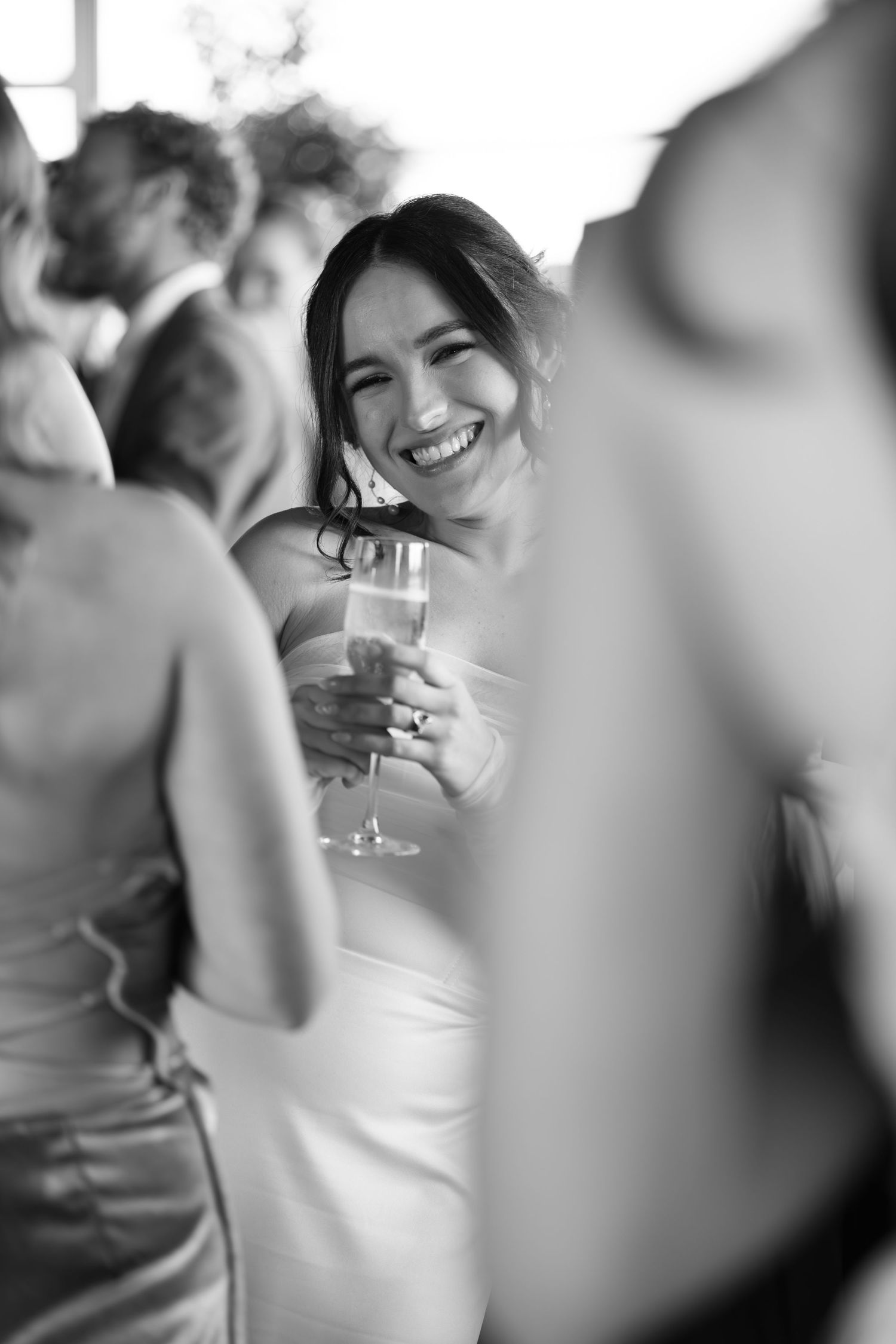 Black and white candid photo of wedding guests enjoying champagne at the reception.