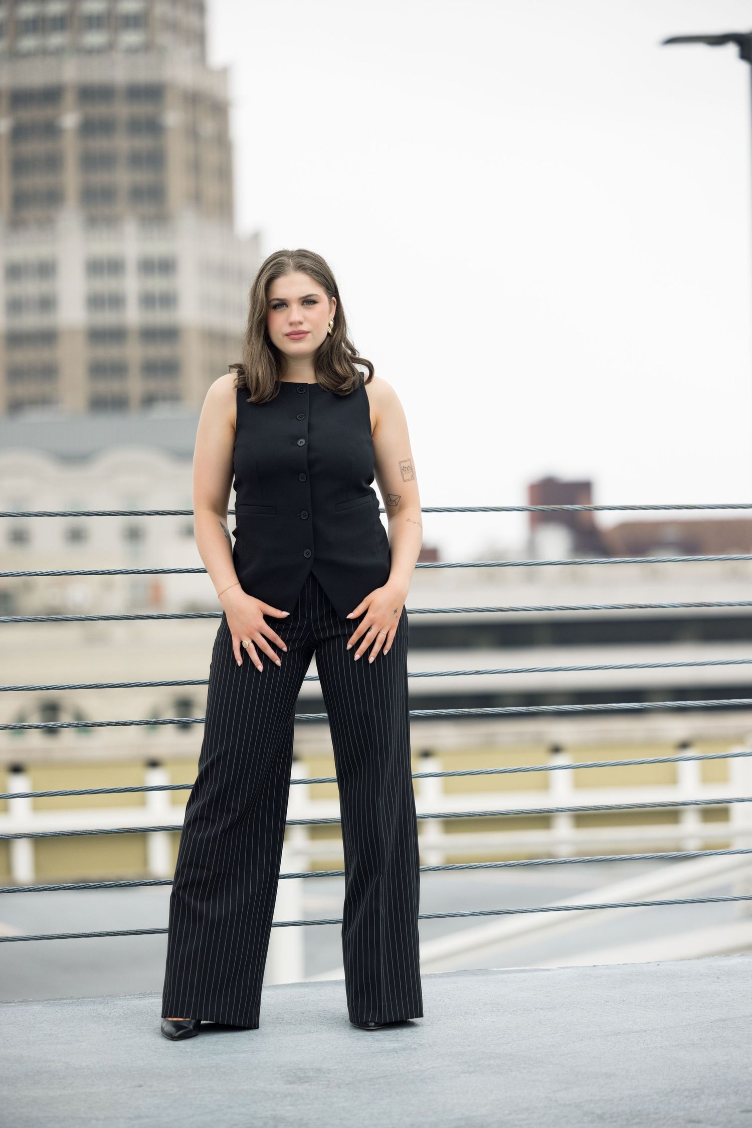 Contemporary fashion poses against downtown skyline on concrete rooftop.