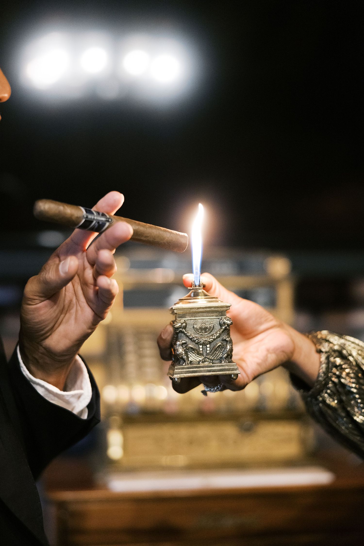 Close-up shots of hands lighting cigars with vintage lighters.