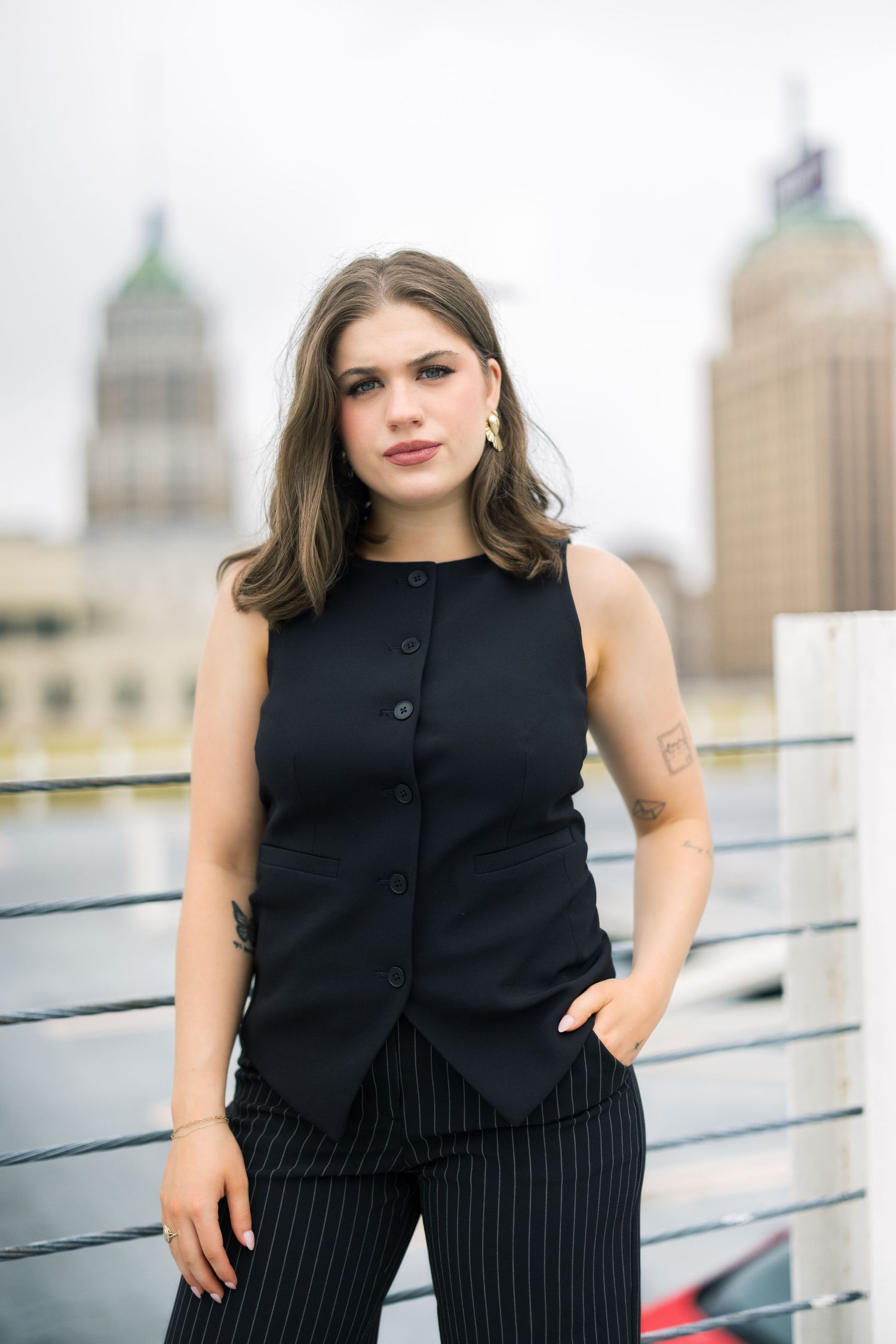 Professional portrait of person in black vest against urban skyline backdrop.
