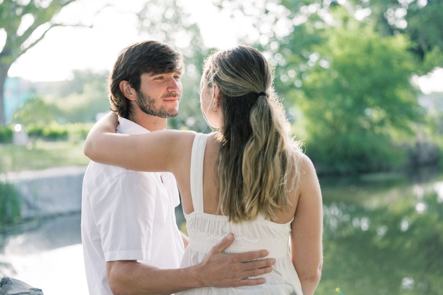 A couple shares intimate moments while relaxing outdoors near a waterfront.
