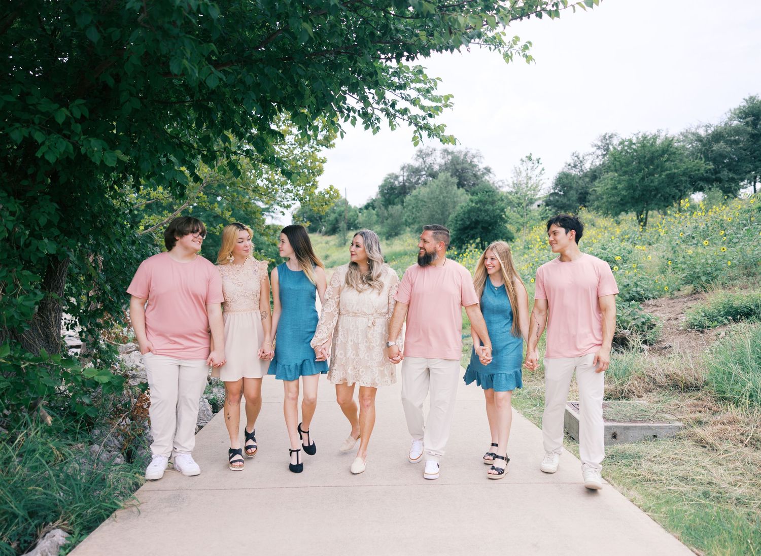 Group walking in coordinated outfits of pink, blue and white along a stone pathway.