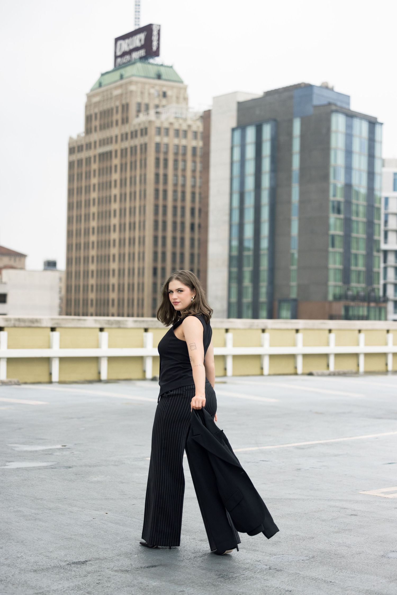 Fashion editorial shoot featuring black ensemble against modern city architecture.