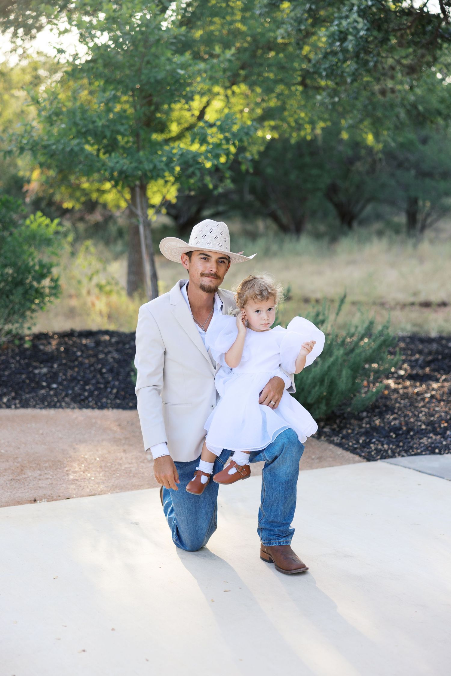 Country wedding photoshoot featuring western boots and white attire against natural backdrop.