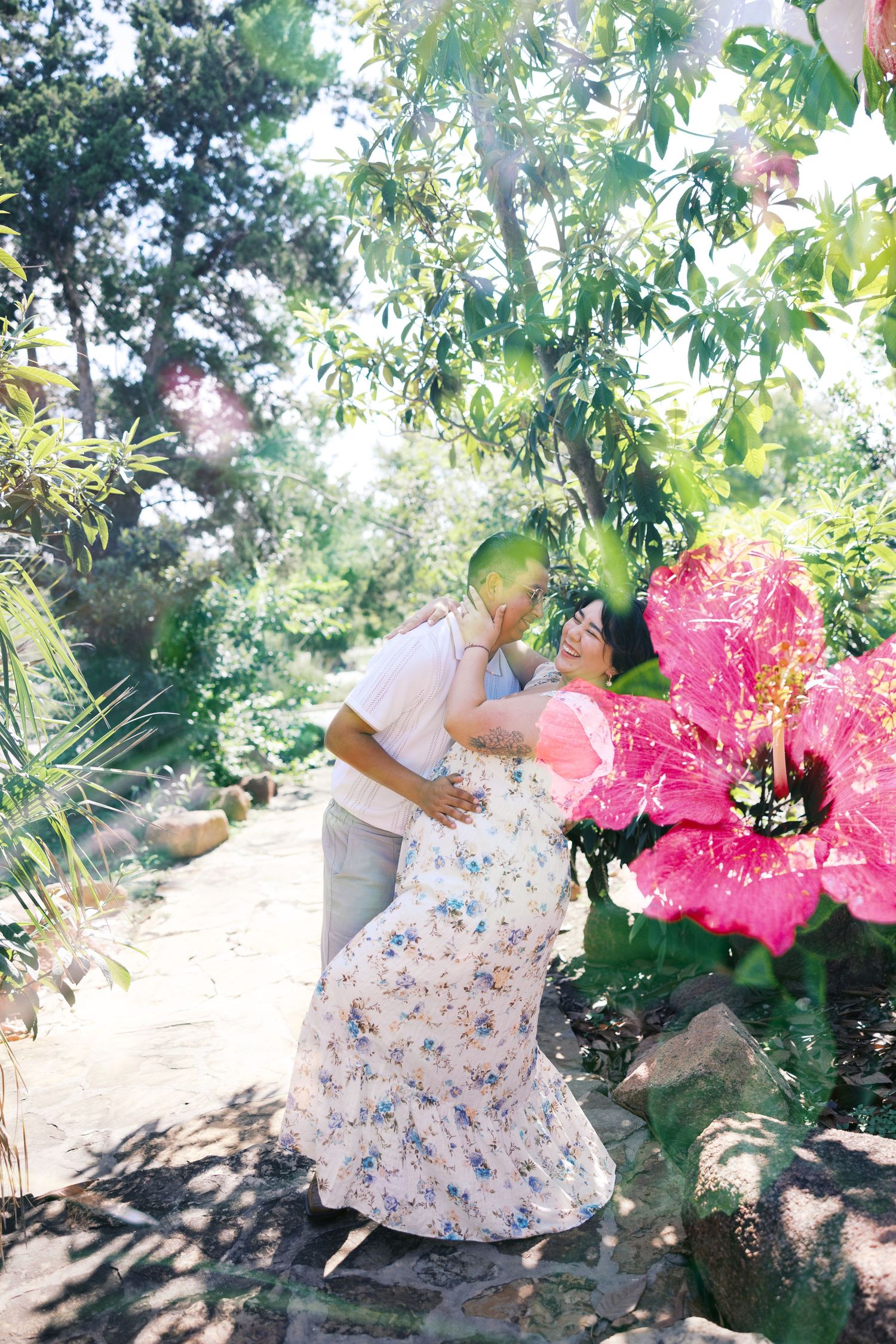 A romantic garden photoshoot with vibrant pink flowers and sunlit foliage.