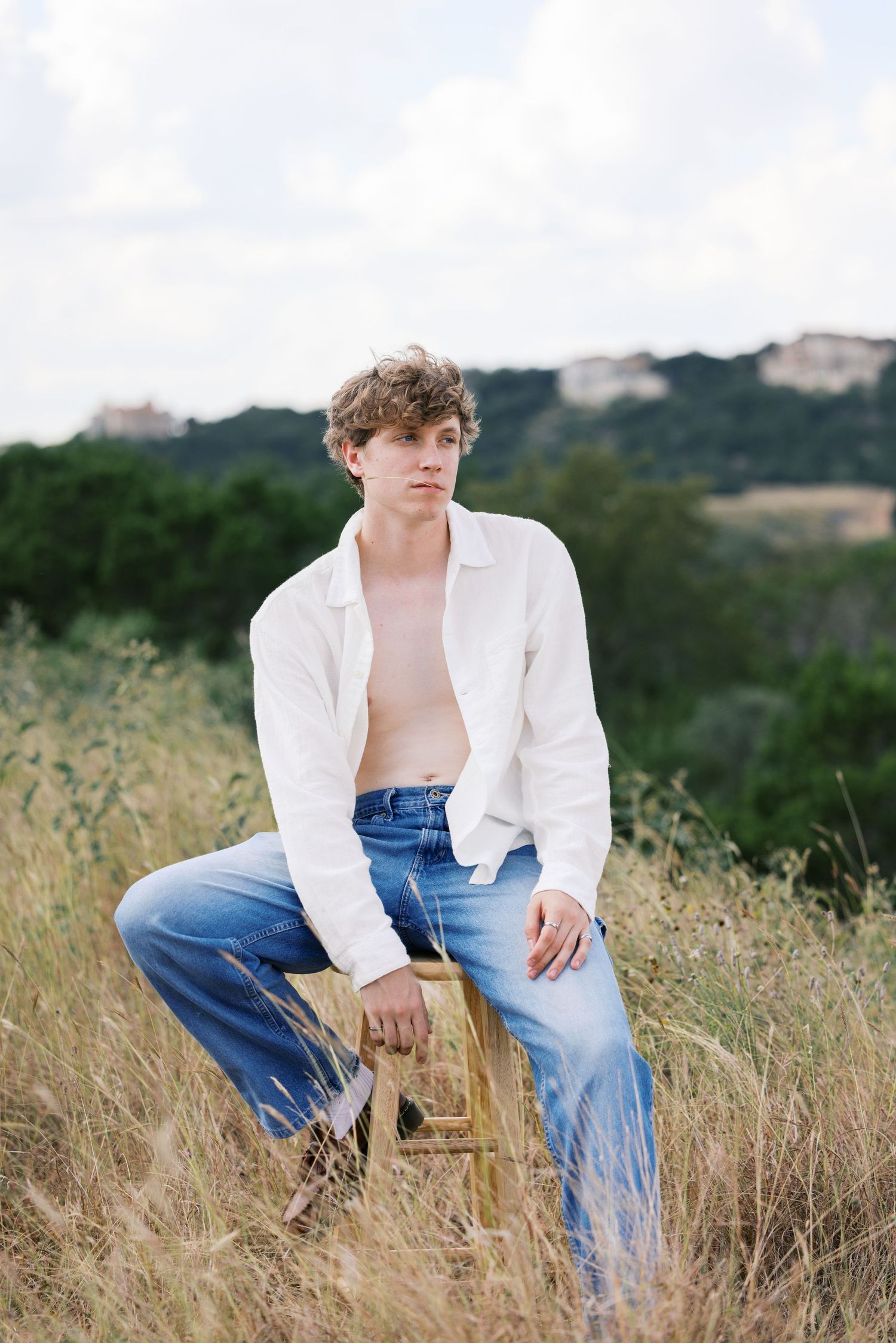 Casual outdoor photoshoot featuring denim and white shirt combination in tall grass.