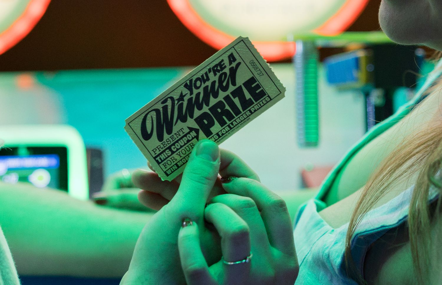 Close-up of arcade game machines with green neon lighting.