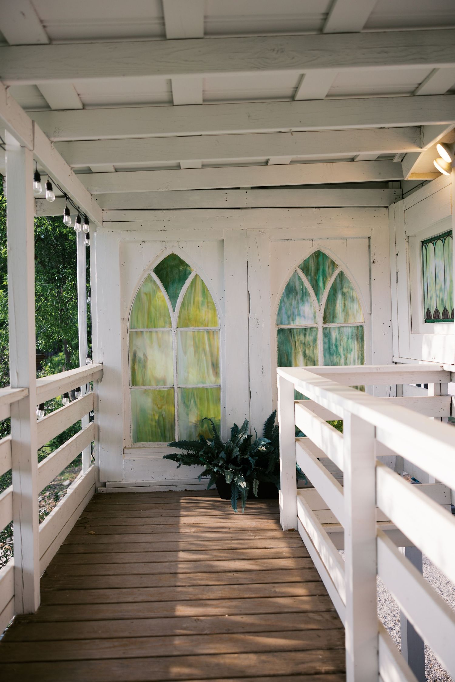 White wooden chapel bridge with arched stained glass windows and wooden railings at a wedding venue.