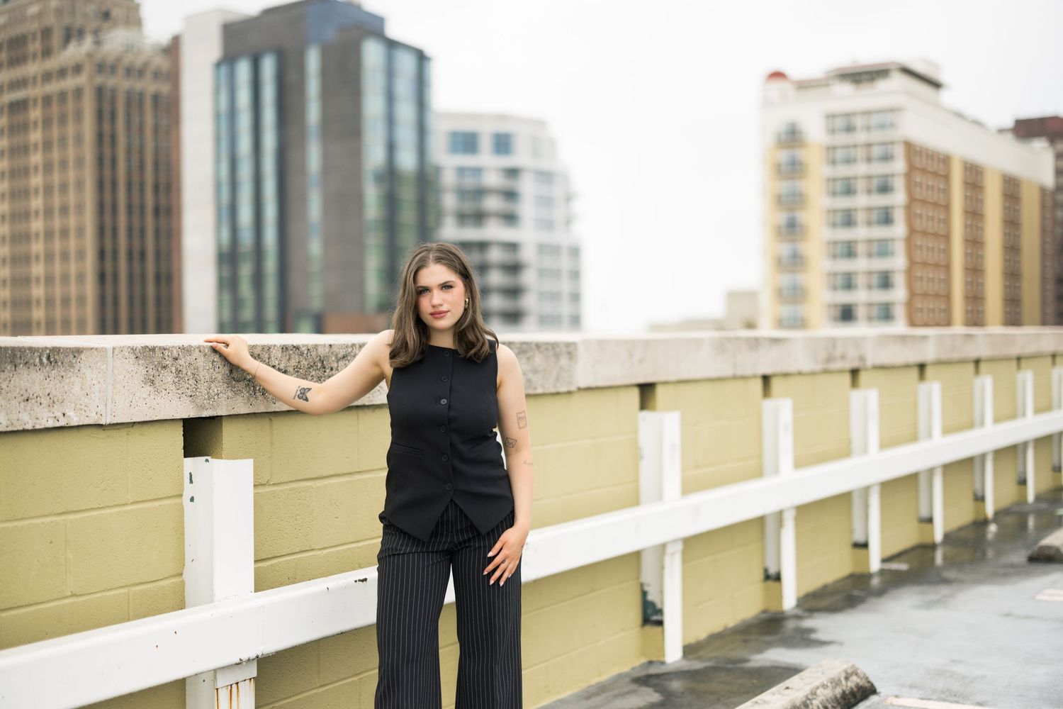 Fashion portrait series on an urban rooftop with modern buildings in the background.