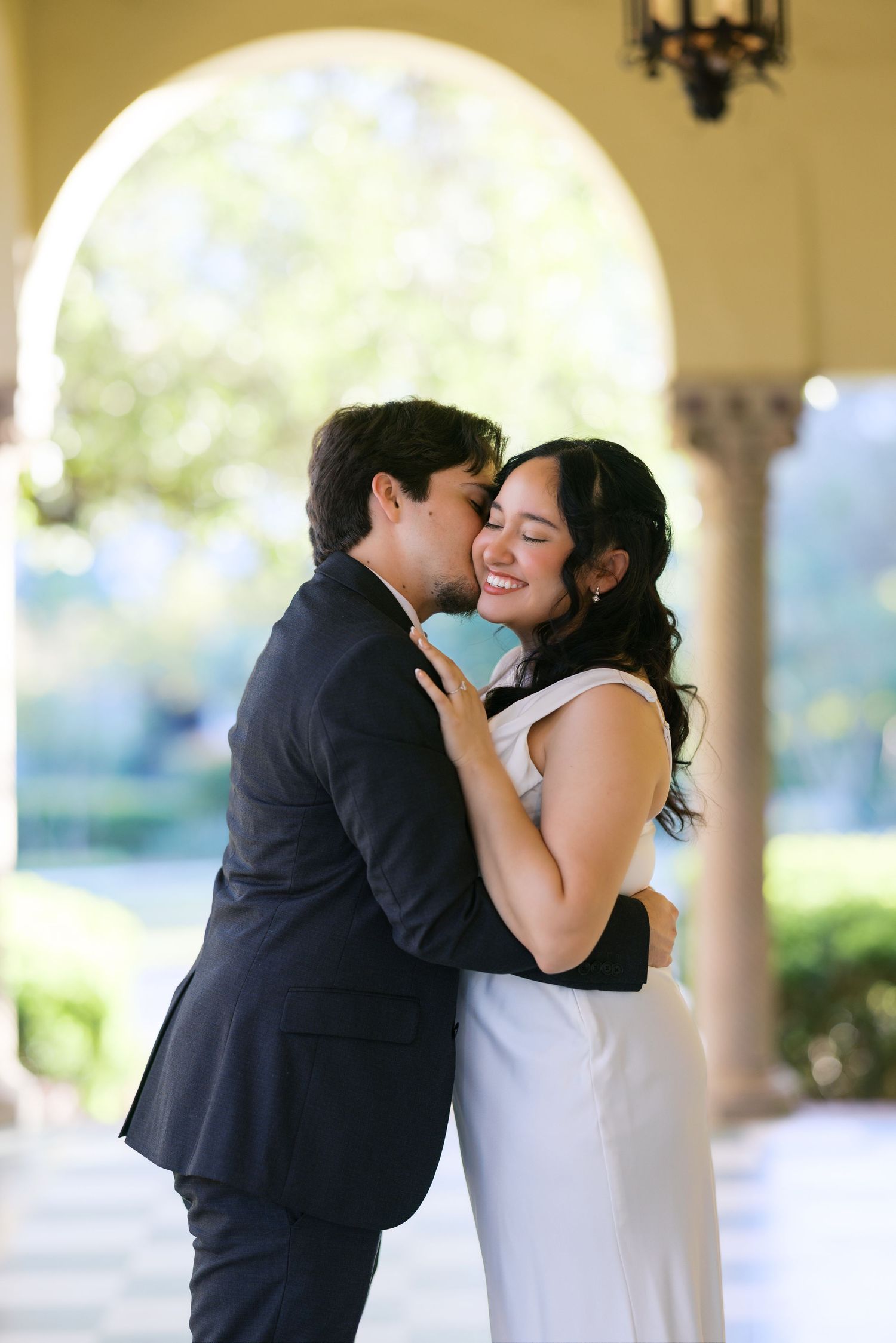A romantic moment shared between a couple in an elegant archway setting.