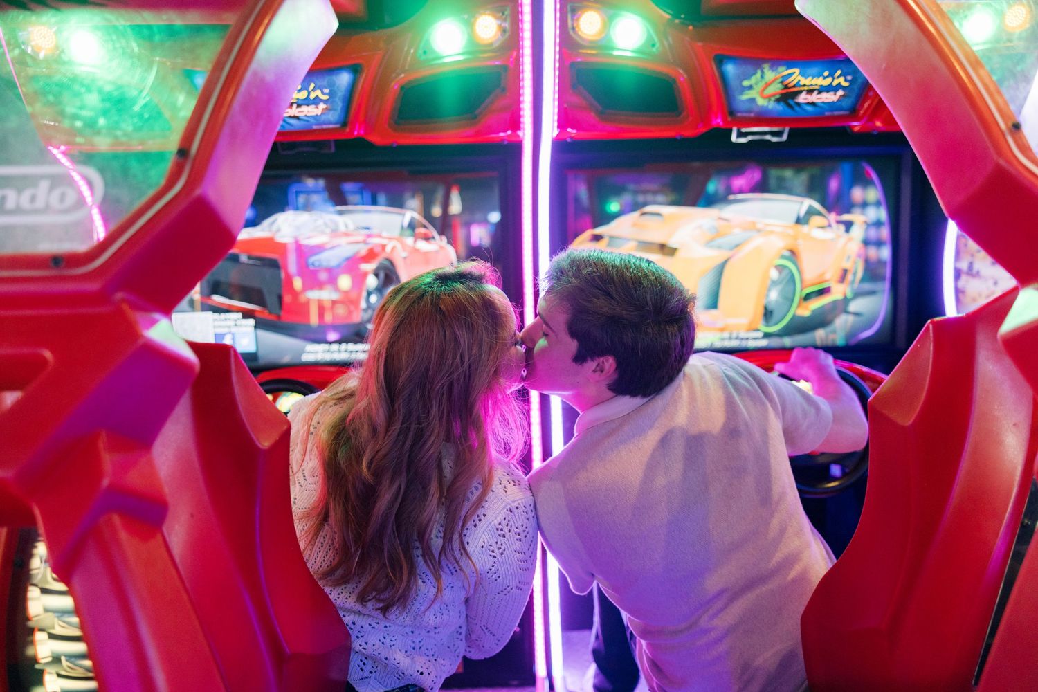 Players enjoying arcade games in a vibrant room with red and green lighting.
