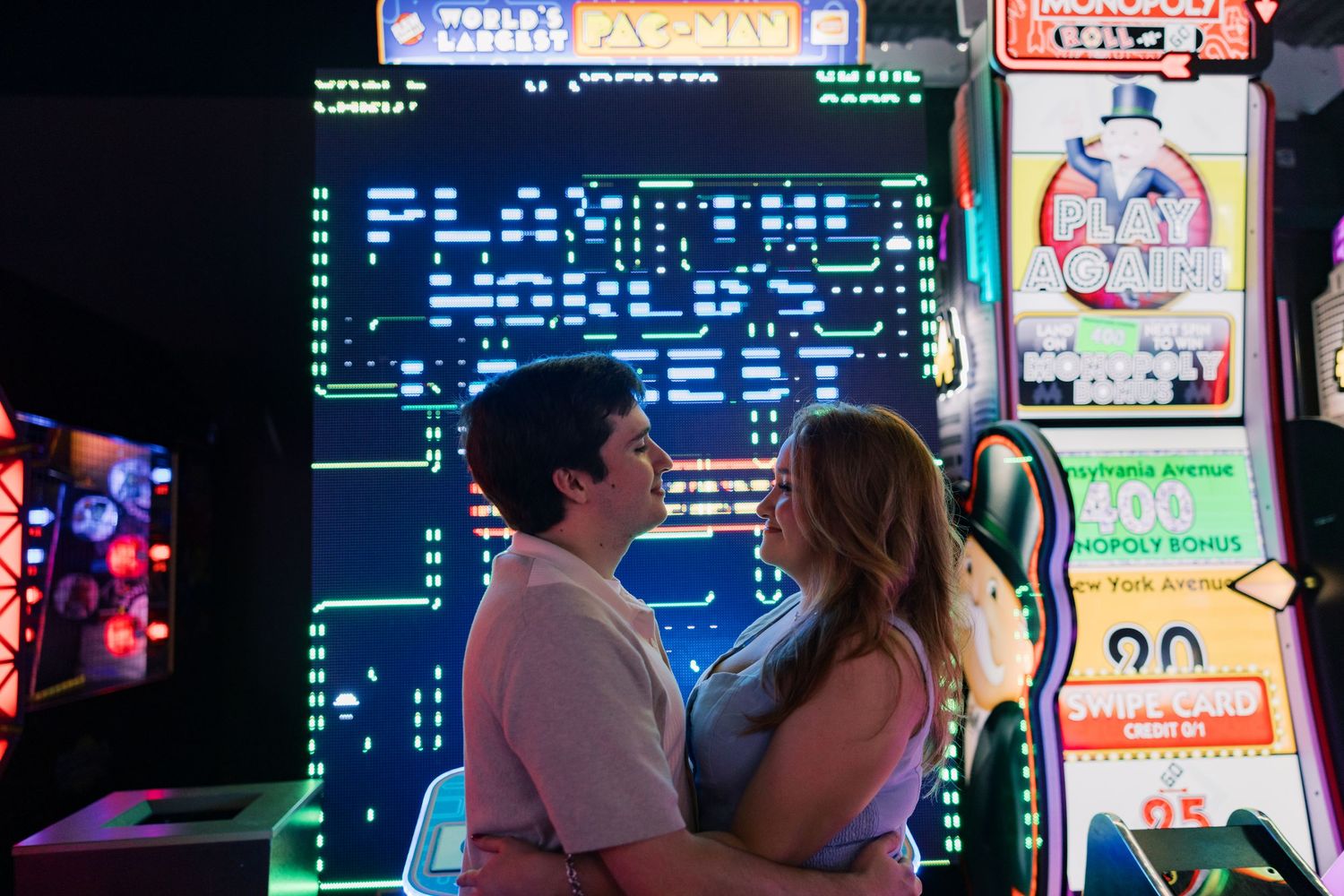 Arcade interior with classic Pac-Man style game displays illuminated in the background.
