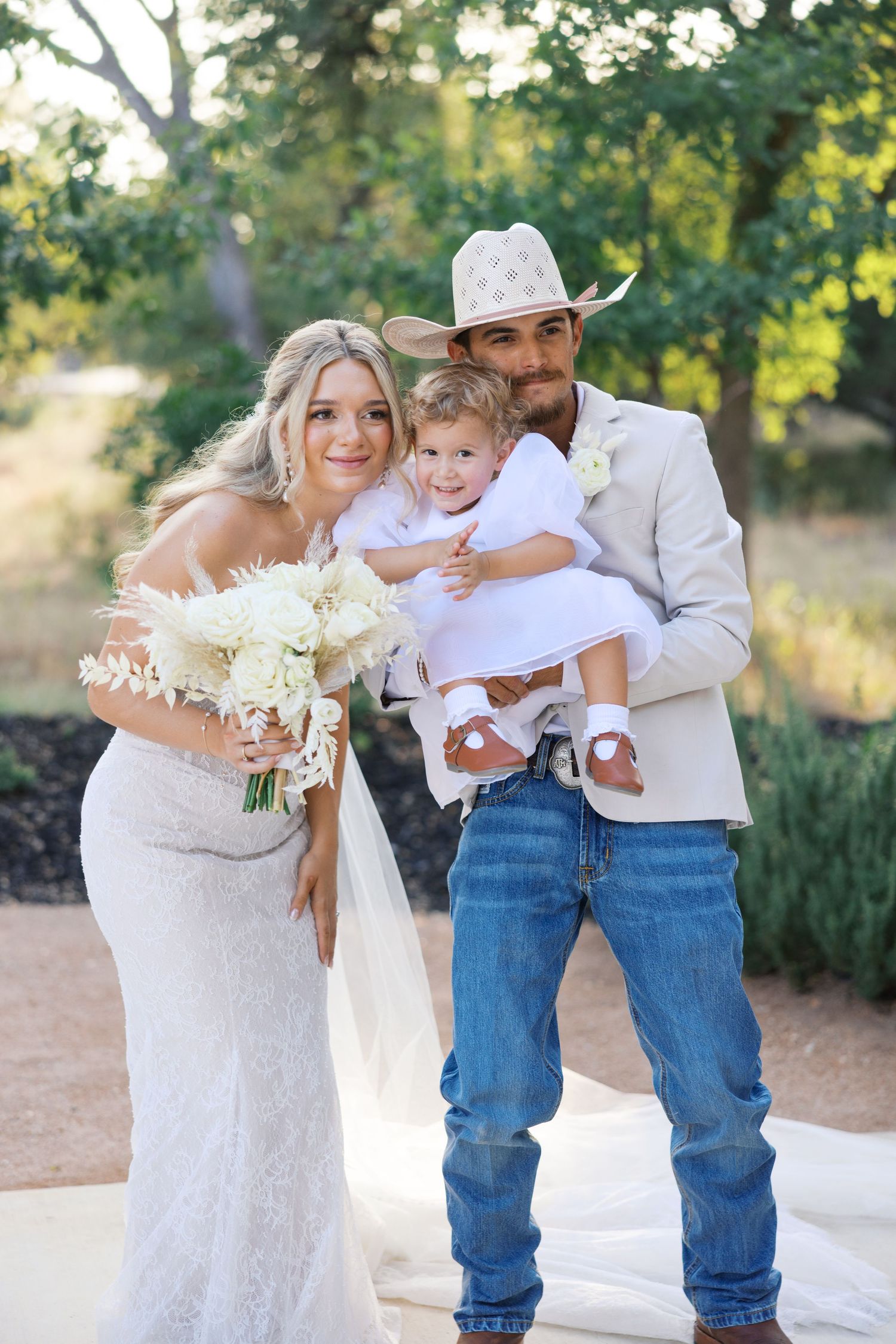 Wedding family portraits in rustic setting with white dress and cowboy attire.