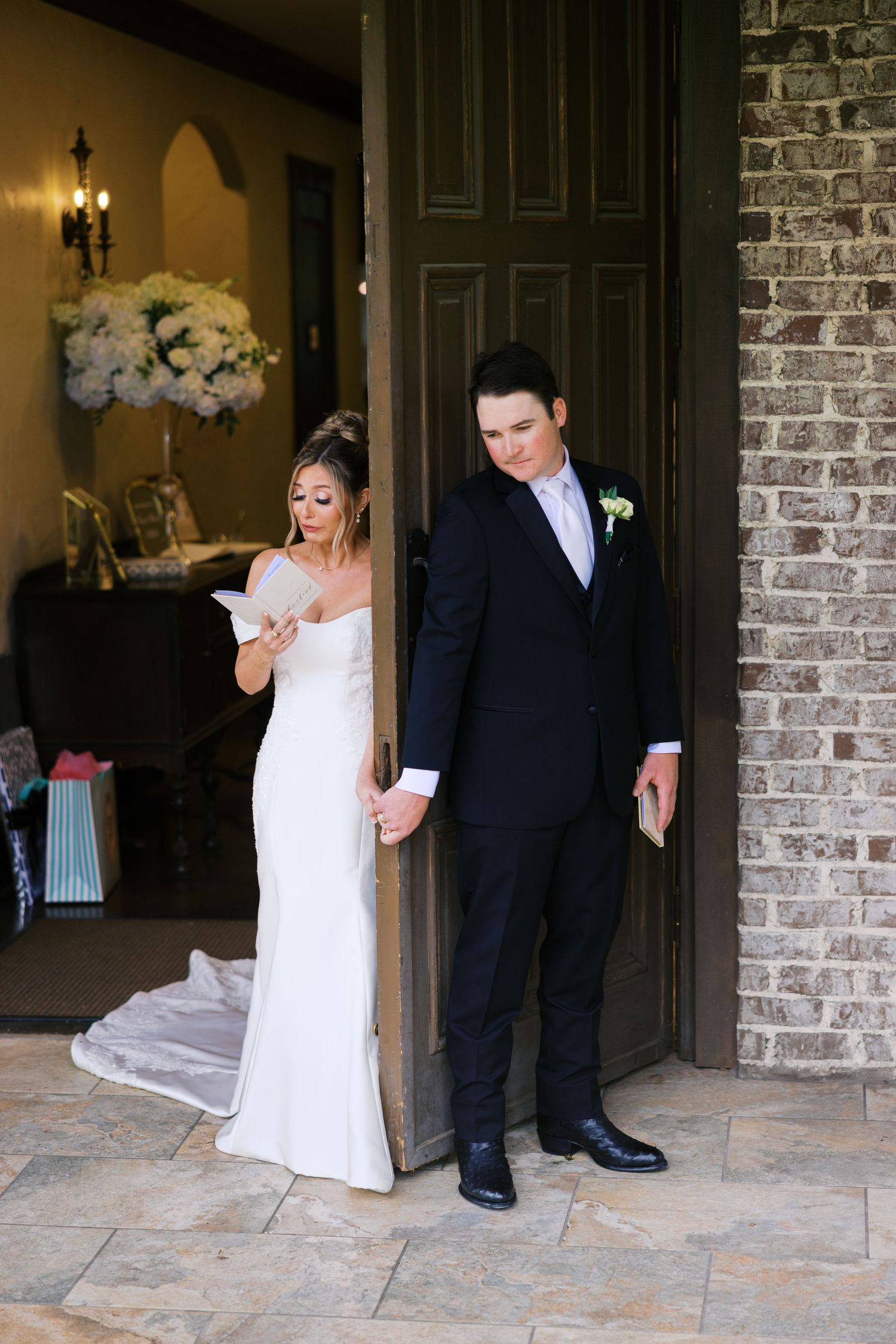 Bride and groom share private vows exchange moment at doorway of brick wedding venue.