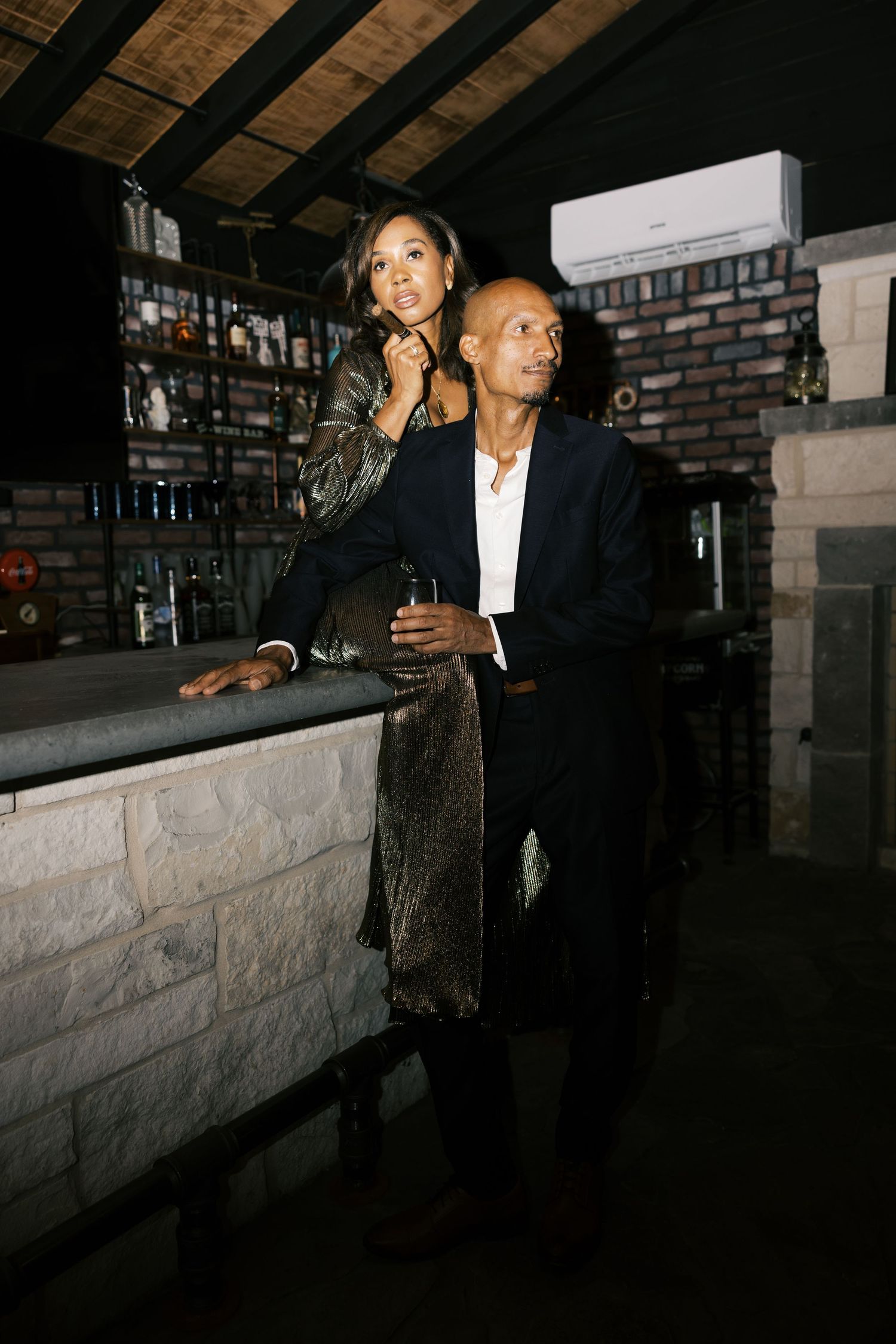 A couple enjoys drinks together at a dimly lit bar with brick walls.
