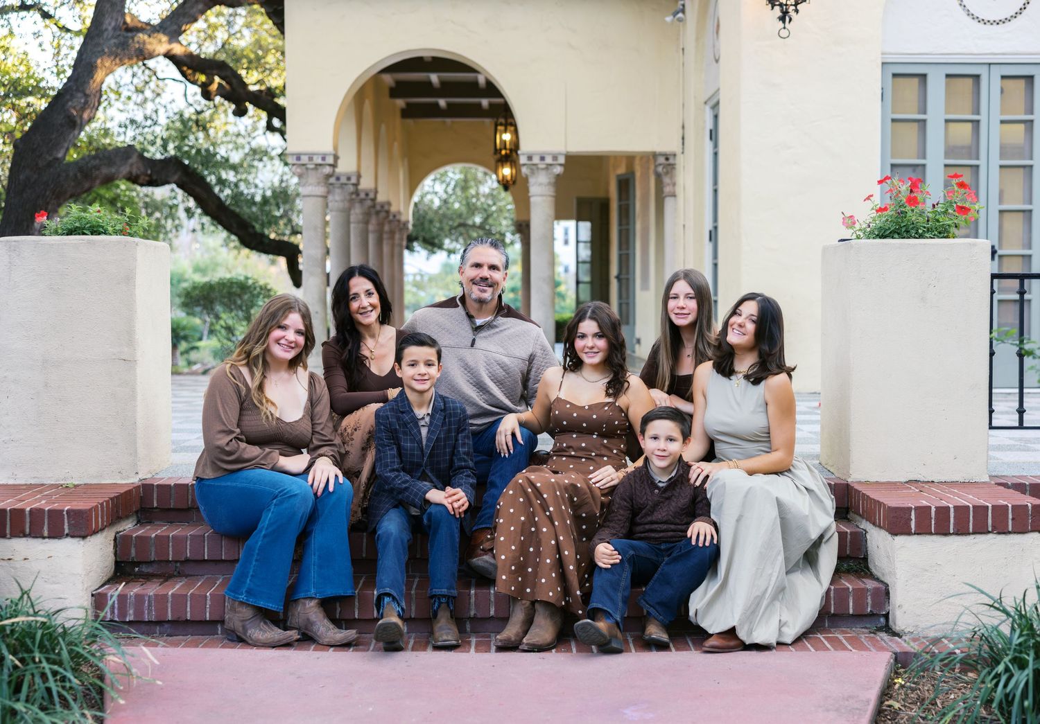 A casual group portrait on the steps of a Mediterranean villa with arched doorways.