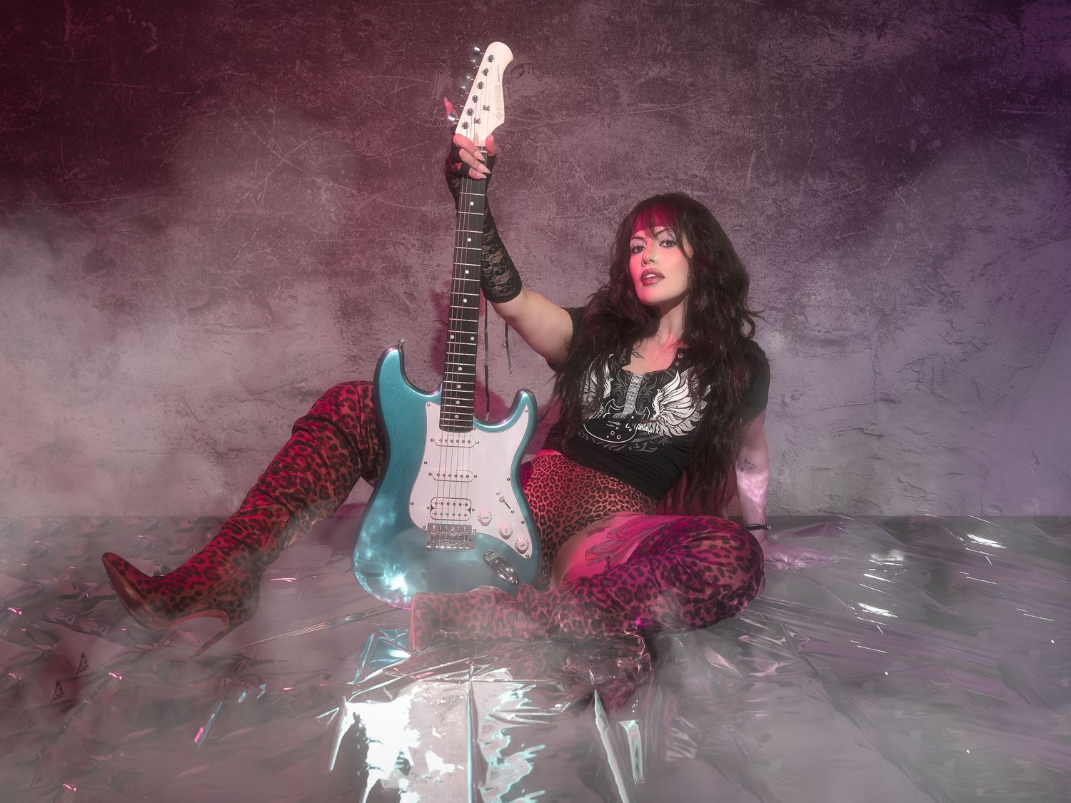 An electric, creative portrait of a model with an 80s glam aesthetic and pops of pink and purple lighting.
