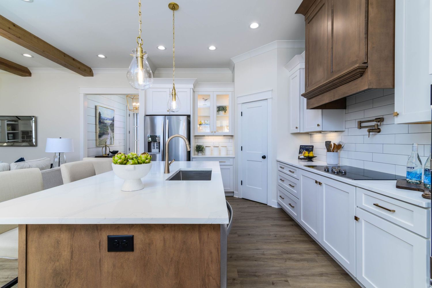 Spacious open-concept kitchen with white cabinets, wood island, stainless steel appliances, and hardwood floors.