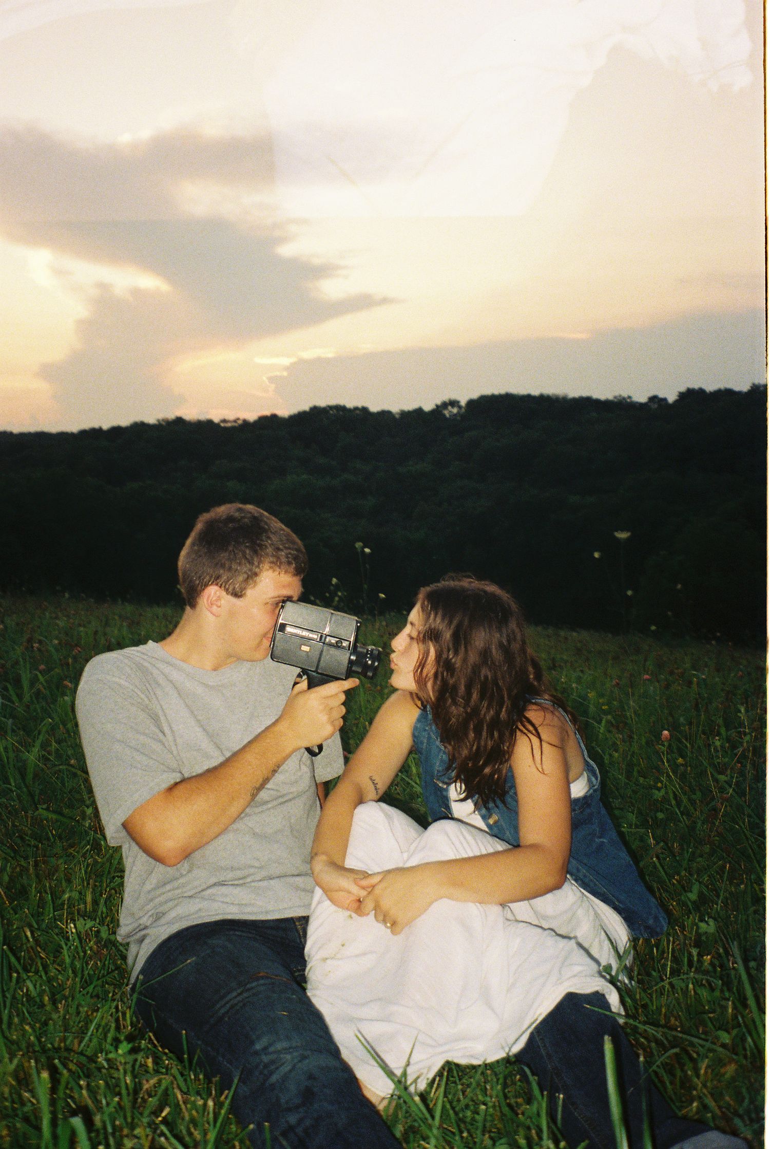 35mm film candid of young adventurous couple holding super 8 camera during sunset
