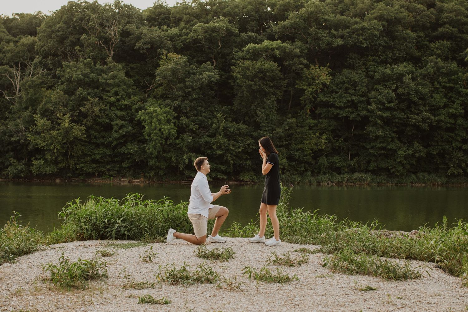 a man proposes to a woman in front of a lake