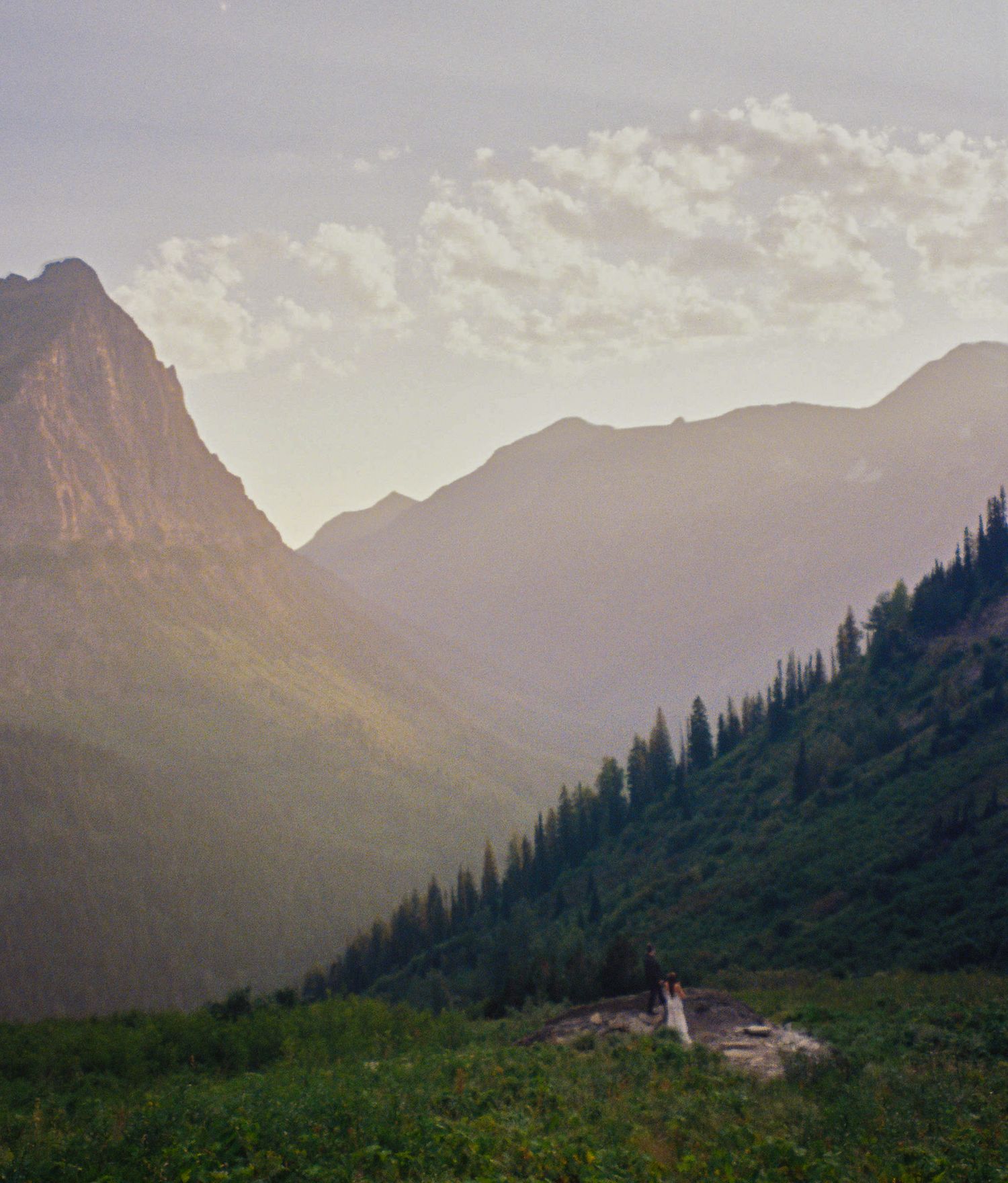 far away photo of couple posing in glacier national park in logan's pass.