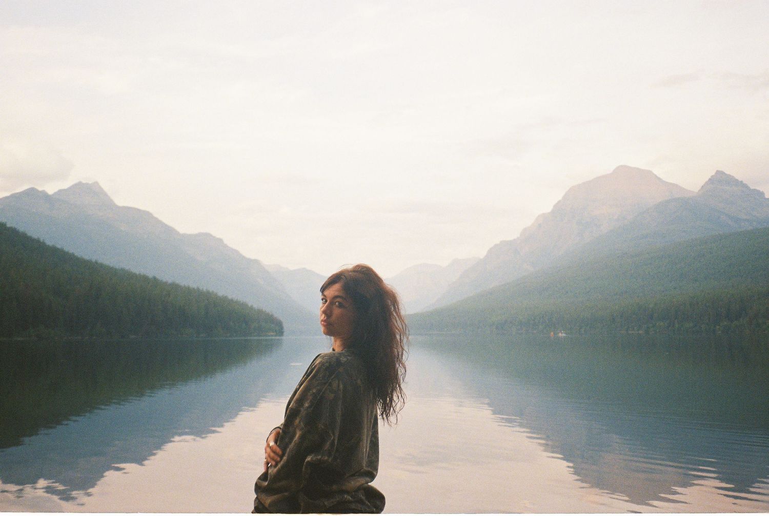 35 mm film of girl in front of a lake near glacier national park in front of the reflections.