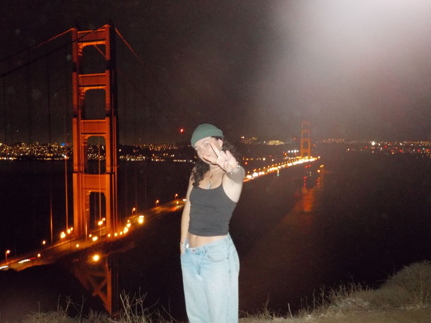 girl poses in front of golden gate bridge at night in san fransisco