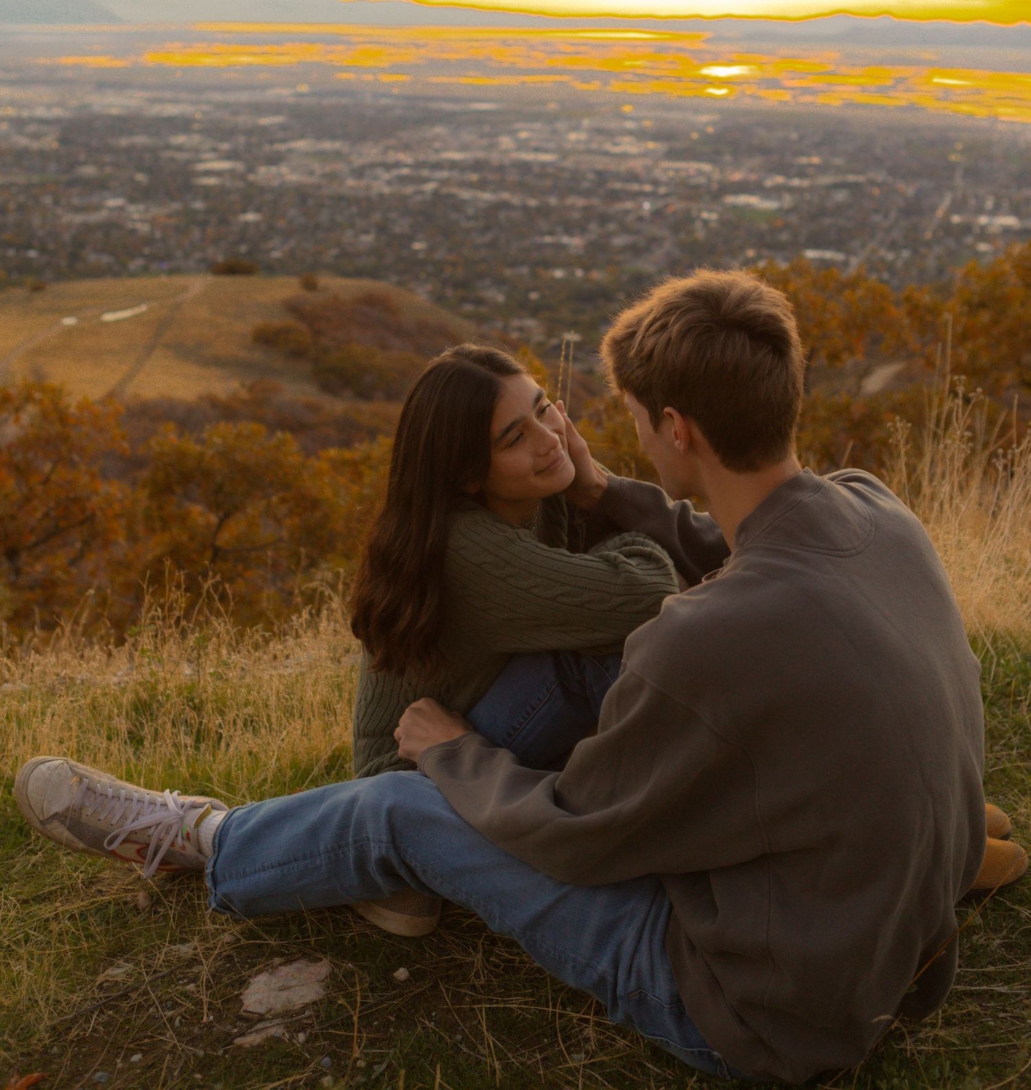 couple looks sweetly at each other in utah during sunset overlooking city