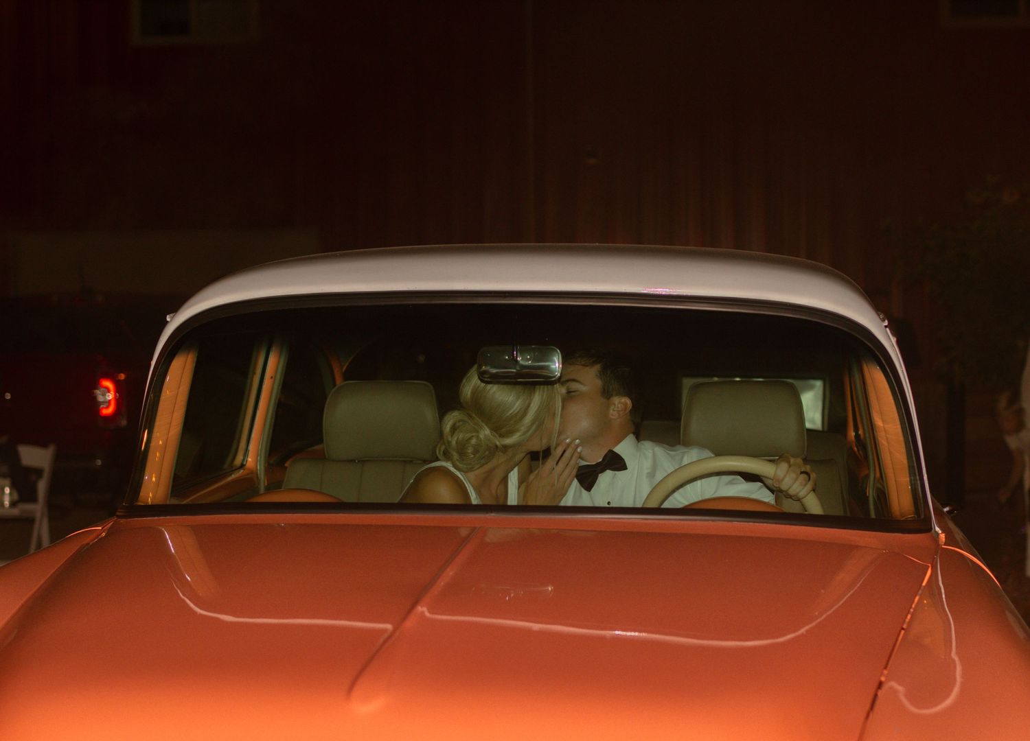 couple kisses in getaway car after wedding reception