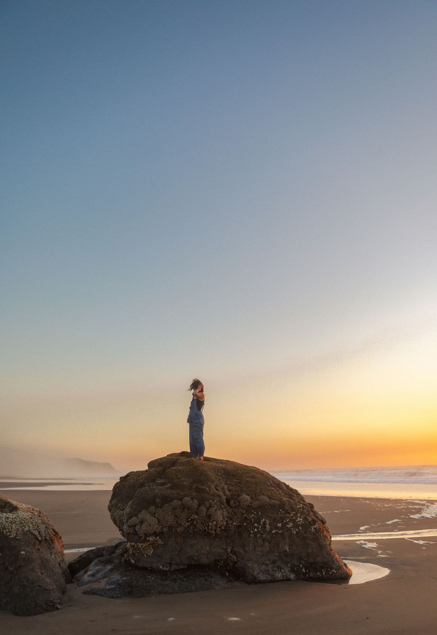 girl poses on rock on oregon coast