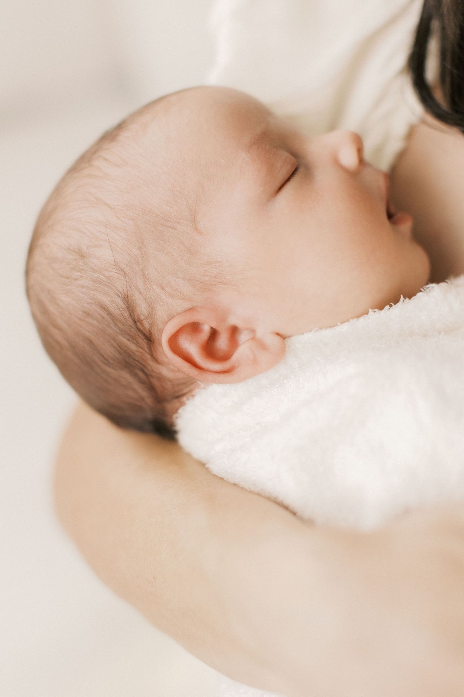 Serene portrait of sleeping newborn in soft white setting.