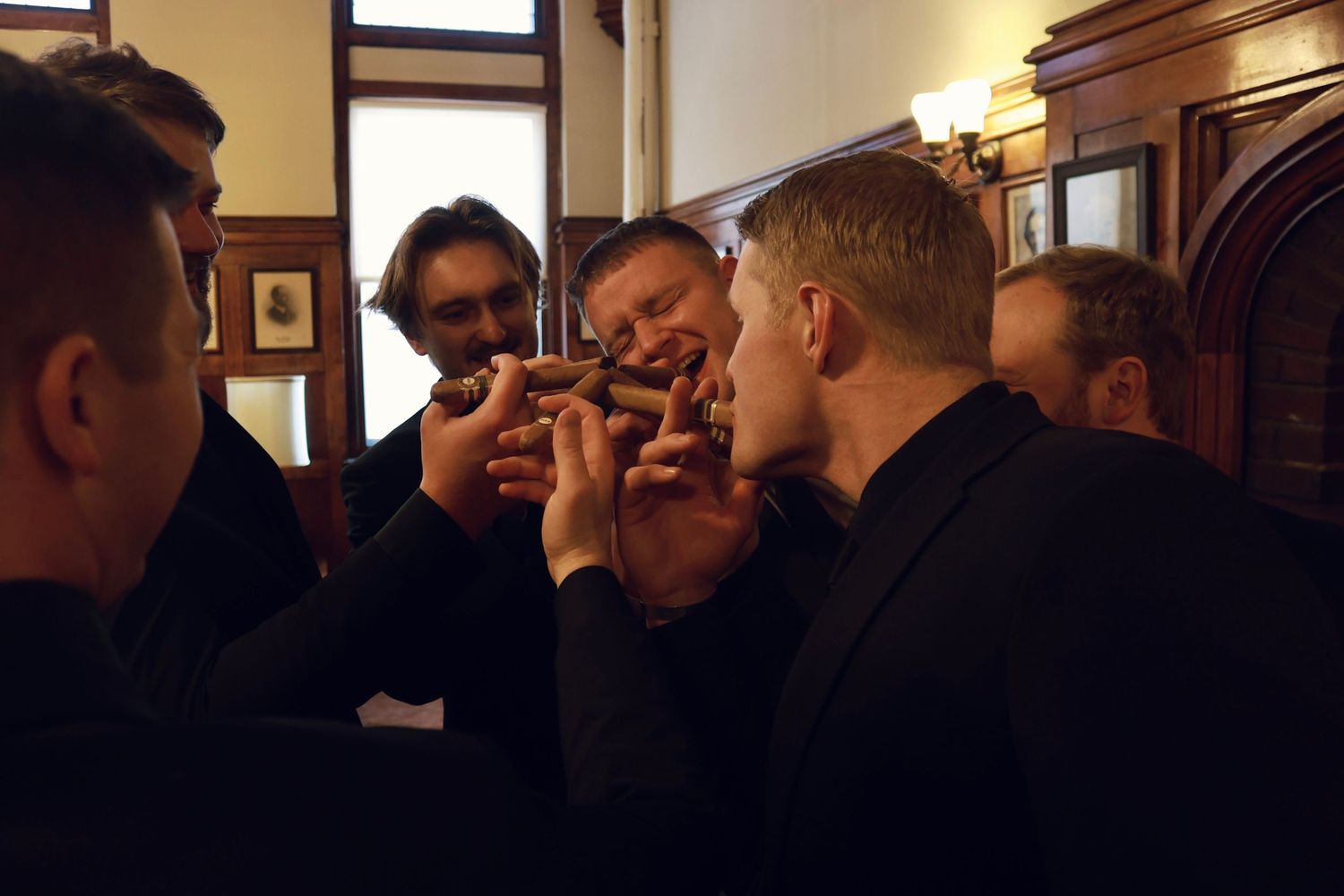 A group in formal attire gathers in a warmly lit hallway with wood paneling.