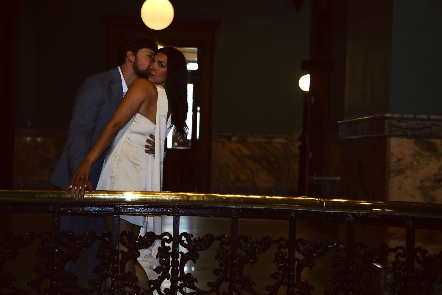 Romantic couple dancing under dim lighting at an evening event.