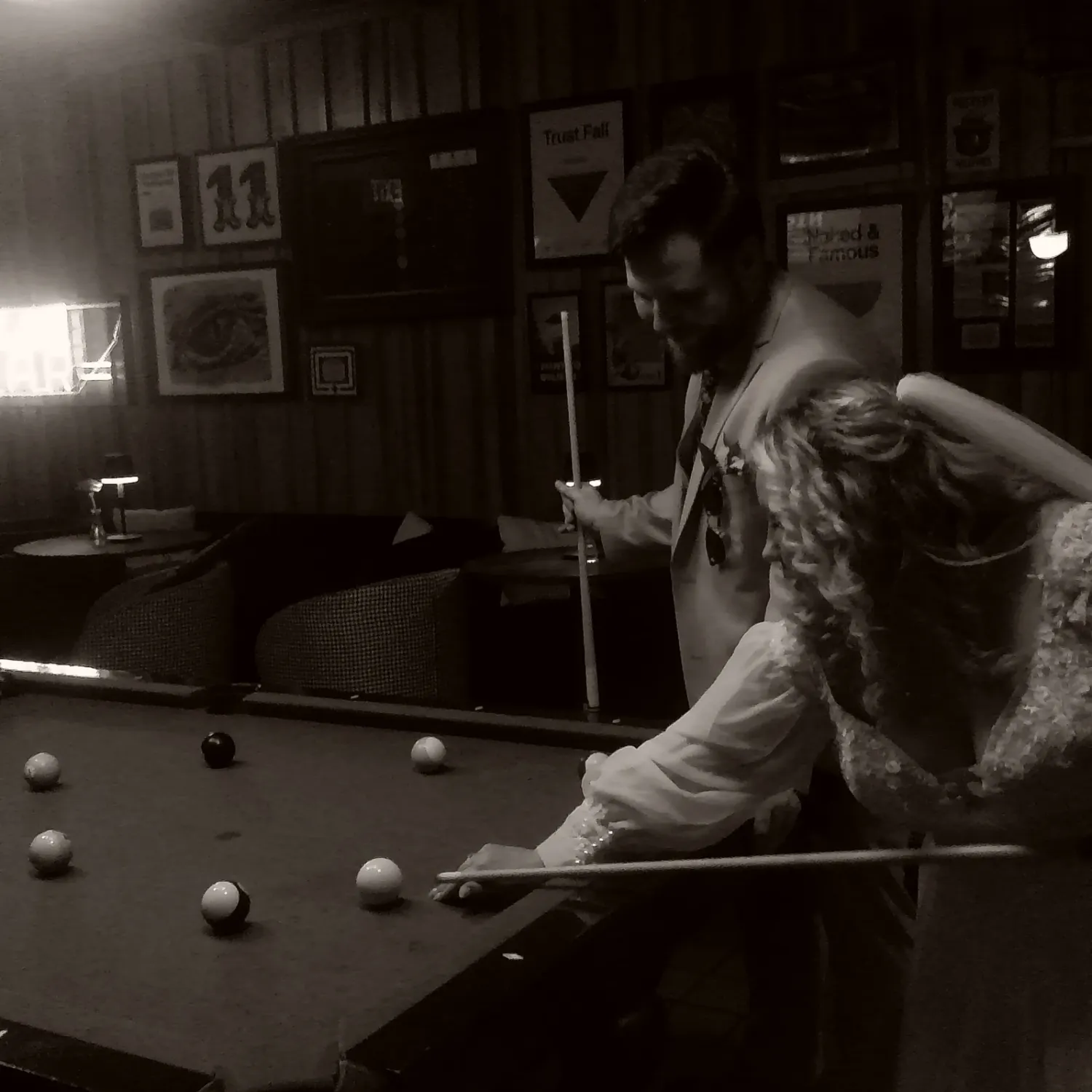 Dark atmospheric shot of people playing pool in a dimly lit room.