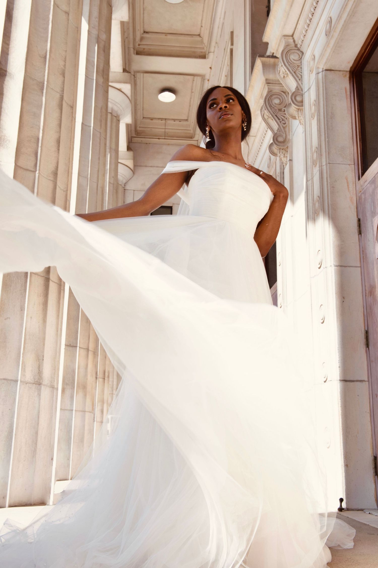 Ethereal bridal gown spinning gracefully in a marble columned corridor.