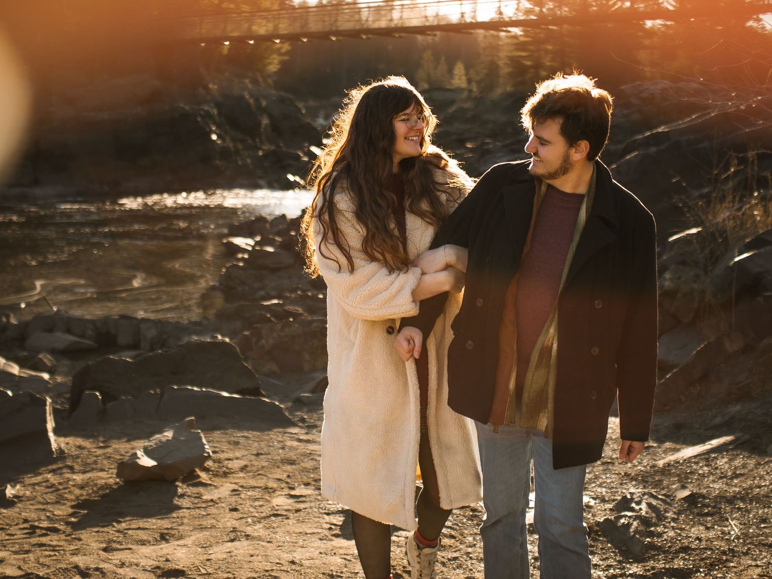 Romantic couple embraces at sunset in a golden-lit outdoor setting.