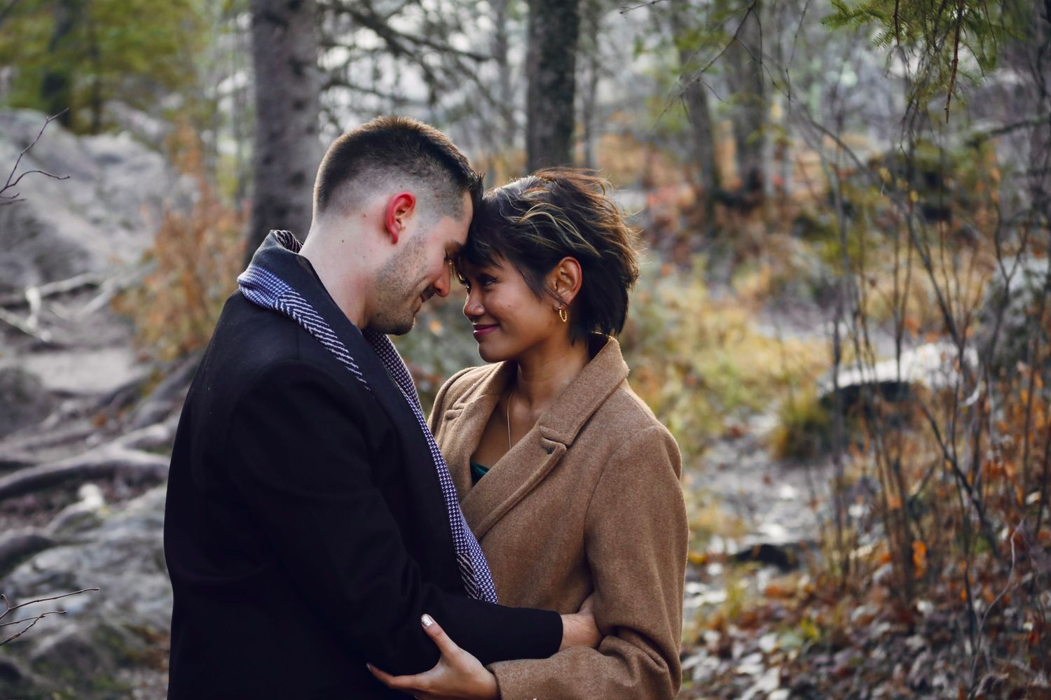 A romantic winter engagement photoshoot among pine trees and rocky terrain.