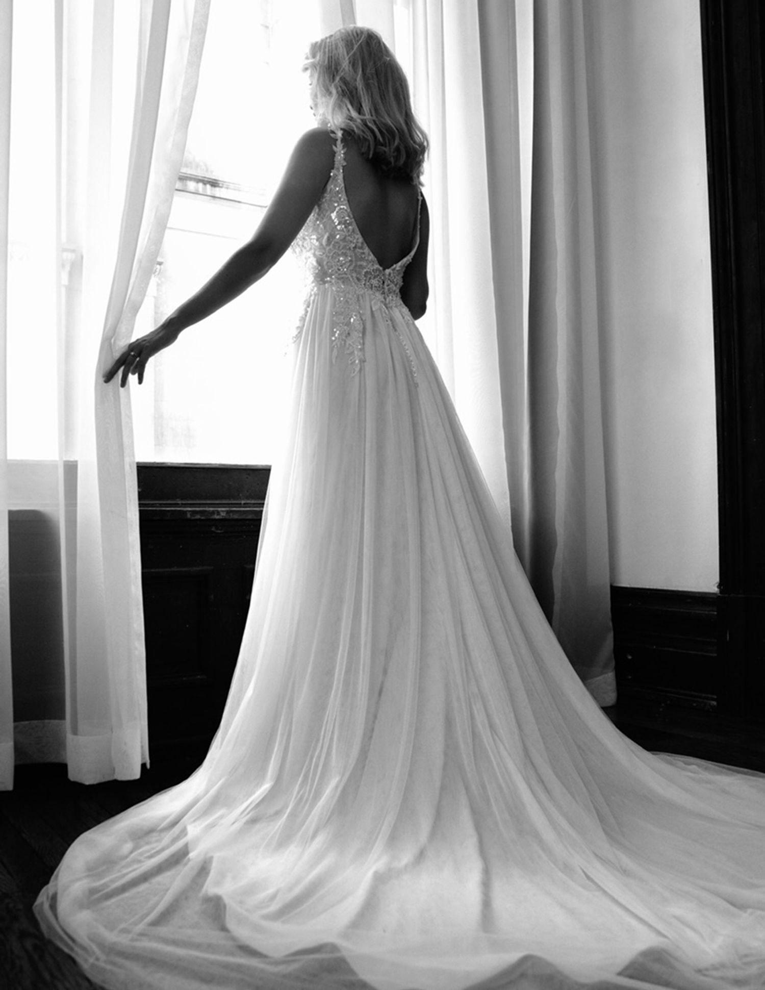 Black and white silhouette of wedding dress train in window light.