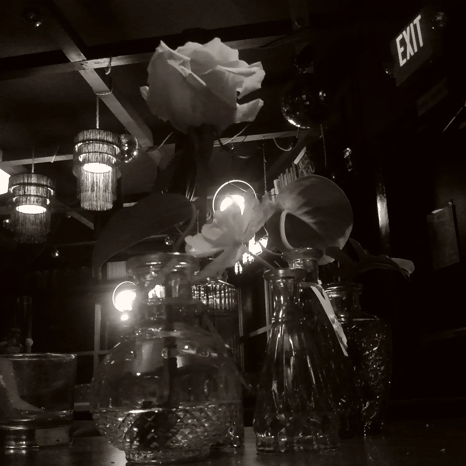 Black and white nightclub scene with illuminated bar and dramatic lighting creating a moody atmosphere.