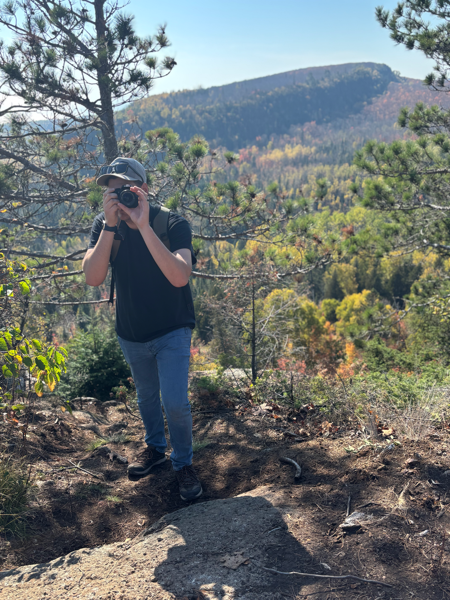 Photographer taking pictures on rocky mountain overlook during fall season.