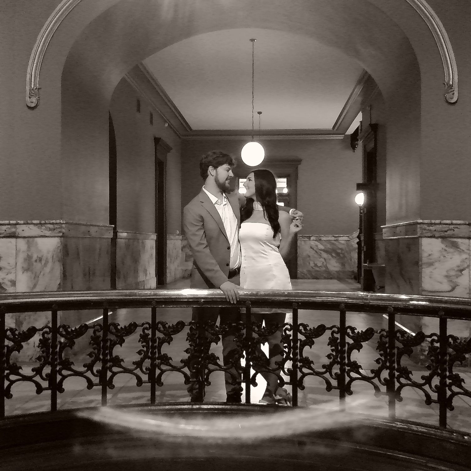 Panoramic view of an elegant ballroom with ornate iron railings and arched architecture.