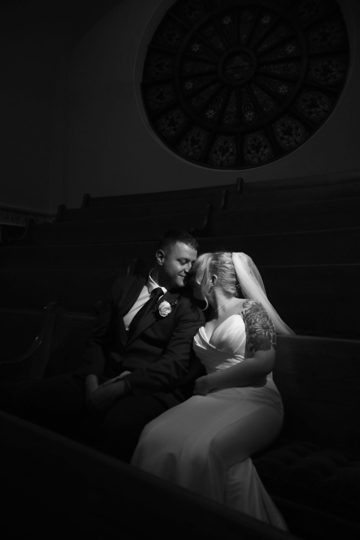 Romantic black and white portrait of newlyweds beneath ornate church ceiling.